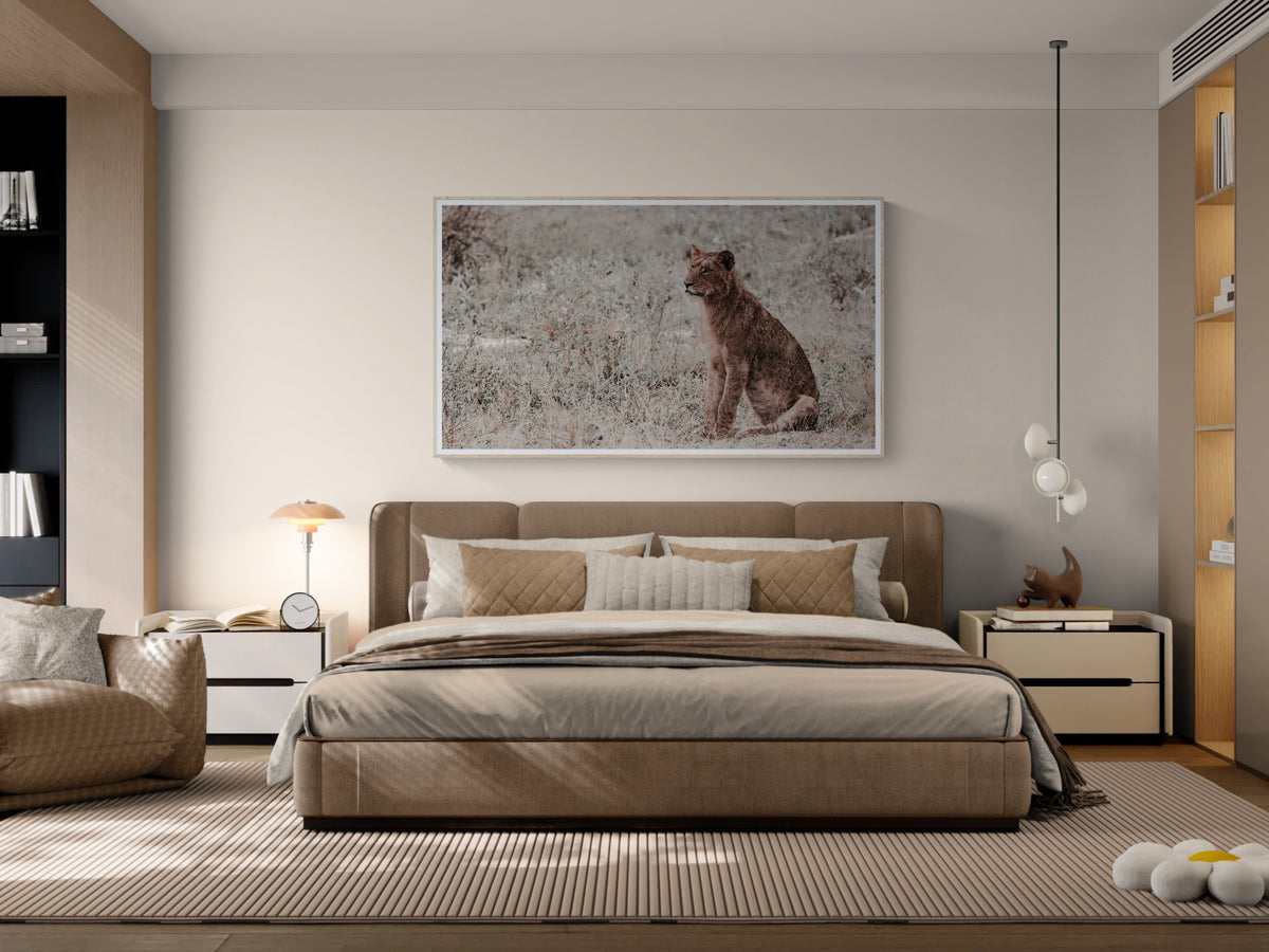 A modern bedroom featuring a large framed art print of Poise depicting a lion cub on the wall above a bed with beige and brown bedding. The room has warm neutral tones, including a striped rug, wooden shelving, and contemporary bedside tables.