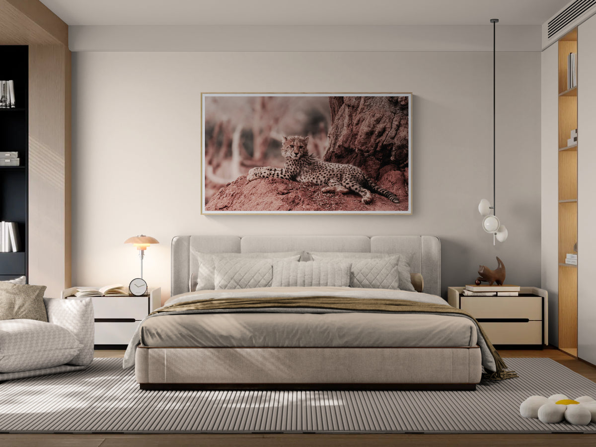 A modern bedroom featuring a large framed wall fine art print of a cheetah cub resting on a tree trunk, hung above a bed.